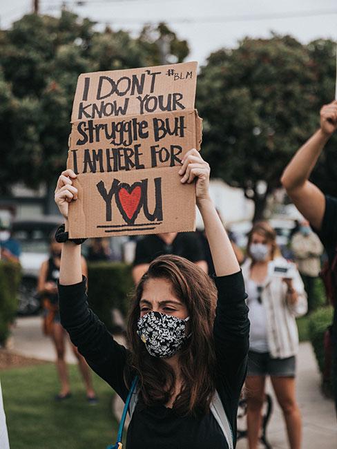 Kobieta w masce protestuje z transparentem